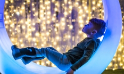 Young boy sitting in a wheel looking up at lights
