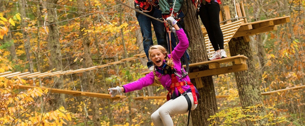 girl riding a zipline through the trees